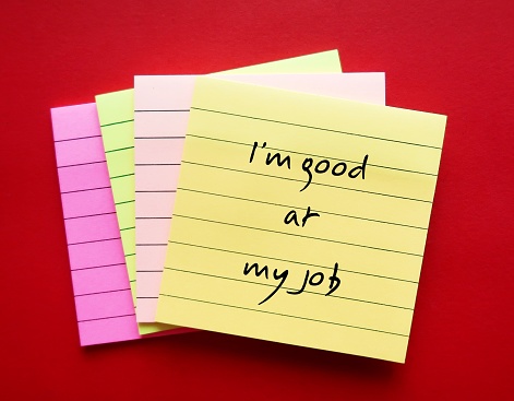 Office note pad on red background with handwriting - I am good at my job - positive self talk affirmation for self motivation at work
