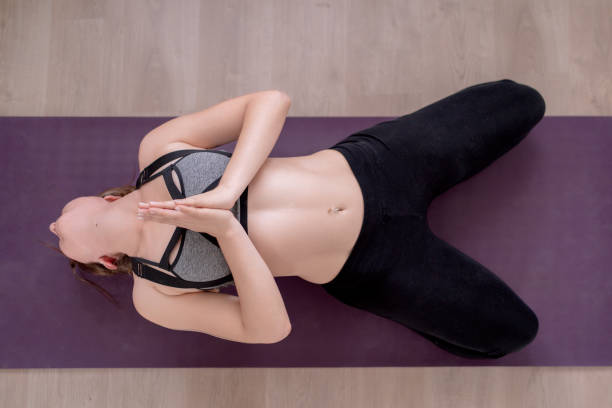 istock Top view of a woman meditating in Matsyasana pose on a yoga mat. 1662943098