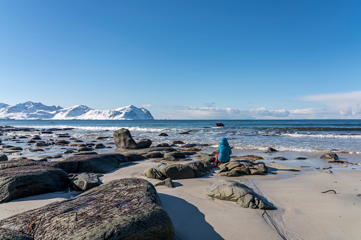Women sitting on boulder at Utakleiv beach, winter, Steinsfjorden. Vestvagoya-Nordland fylke-Norway.