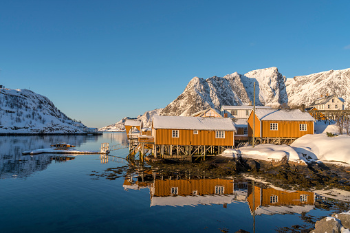 Winter view on wooden cottages in winter at sunrise in village of Raine on tiny island in the Lofoten archipelago in Norway.