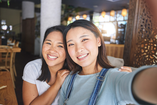 Selfie, love and an LGBT couple in a restaurant for a romantic date together on their anniversary. Portrait, smile and a happy asian woman with her lesbian partner in a cafe for a celebration