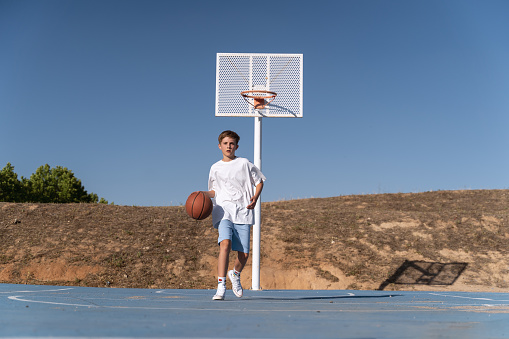 Young boy playing basketball on an outdoor basketball court. Sports concept.