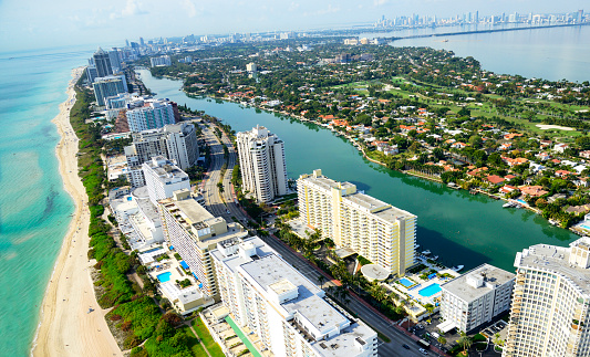 Bal Harbour, USA - May 8, 2018: Wealthy rich single family home house with dock and boat docked by waterfront in Miami Florida with light green turquoise ocean Biscayne Bay Intracoastal water