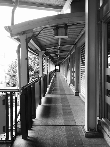 The electric train walkway is empty of people, the black and white color tone conveys loneliness.