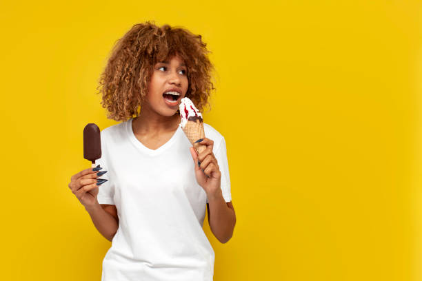 istock curly american girl with braces holding two different ice creams with jam and daydreaming on yellow background 1663010622