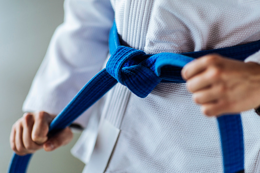 Unidentified young woman tying her blue belt around her white kimono