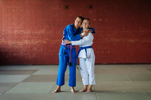 Two female friends pose and hug each other before training