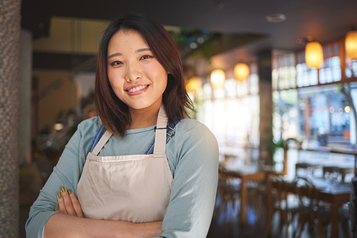 Portrait, happy asian woman or restaurant entrepreneur in small business with arms crossed for professional service. Cafeteria server, coffee shop waitress or confident manager working in hospitality