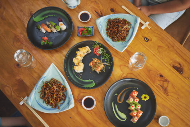 istock Sushi restaurant, catering and table in top view for service, lunch or dinner for people, chopsticks or fish. Japanese cuisine, platter and food in diner, cafe or luxury for health, nutrition or diet 1663011628