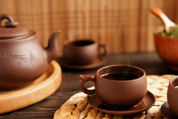 istock Tea Ceremony. Traditional Asian Tea Utensil, Serving Authentic Set. Person Pouring Tea from Brown Pottery Teapot to Teacup. Bamboo Tray. Lifestyle. Wellness Balance Health. Tea Brewing Equipment 1663012063