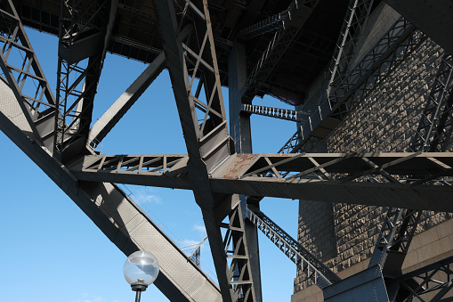 Supporting beams under the Sydney Harbour Bridge with blue sky behind.
