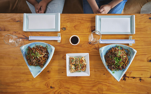 Chinese food, sushi and noodles on a table in a restaurant from above during a date in an asian eatery. Seafood, cuisine in a bowl and a traditional dish for hunger, nutrition or diet closeup