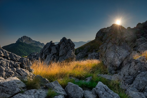A scenic view of rocky hills covered with green grass at sunrise