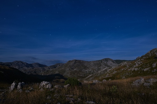 A scenic view of a green mountain range under a starry night sky