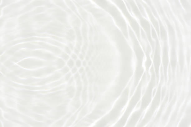 White water with ripples on the surface. Defocus blurred transparent white colored clear calm water surface texture with splashes and bubbles. Water waves with shining pattern texture background.