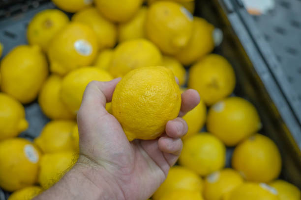istock Person holding a lemon in a supermarket. 1663058839