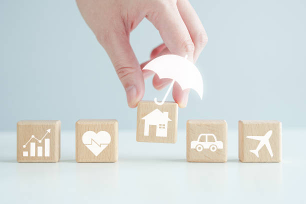 istock Insurance concept. Protection against a possible eventuality. Hand holding umbrella icon for security symbol and house, car, health care, business and travel on wood block for assurance life concept. 1663064920