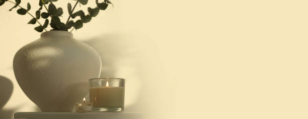 istock Leaf eucalyptus bouquet in bowl and burning candle on beige interior. Selective soft focus. Minimalist still life. Light and shadow nature horizontal long copy space background. 1663068803