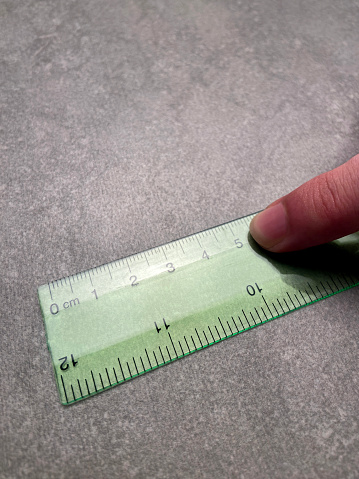 Hand showing 5 centimeters on ruler. High angle view a finger pointing number 5 on ruler with copy space