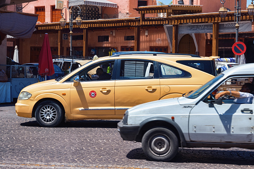 Marrakesh, Morocco - June 05, 2017: View of the yellow taxi car on the road in Marrakech on a sunny day.