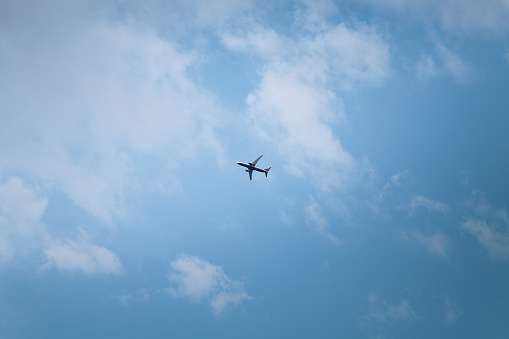 Commercial airplane flying above clouds, backside view. Sunset light