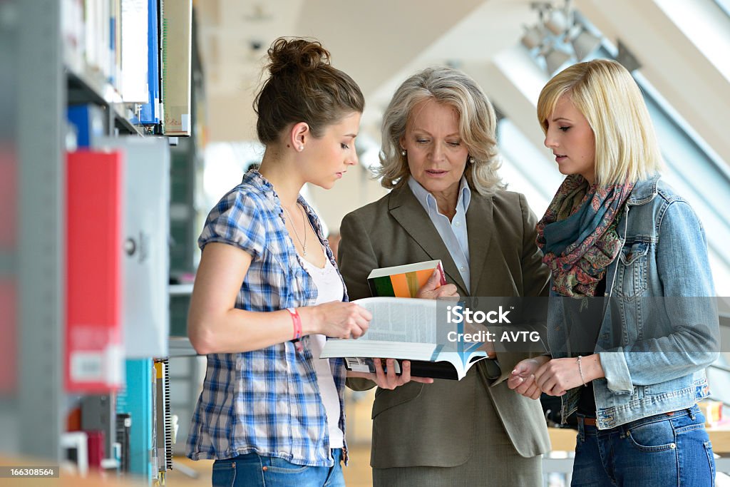 Due studenti con il professore in discussione libro nella Libreria - Foto stock royalty-free di Insegnante