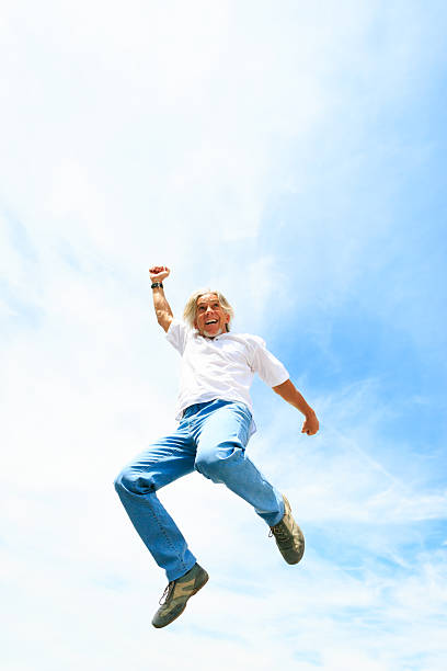 istock man in his 50s jumping high into the sky 166309068