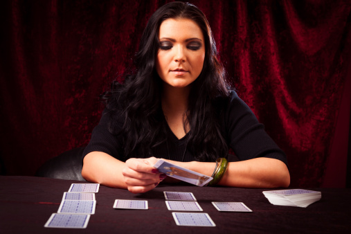 Woman with tarot cards at grey table, closeup