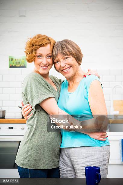 Madre E Figlia In Piedi In Cucina - Fotografie stock e altre immagini di Abbracciare una persona - Abbracciare una persona, Adulto, Allegro