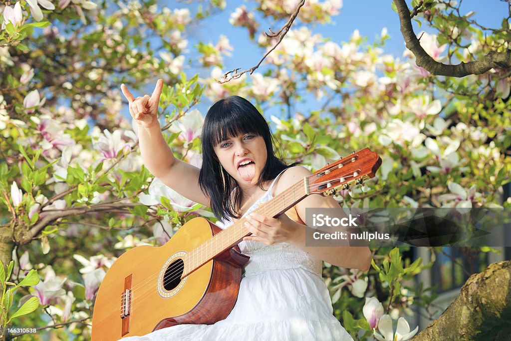not that innocent young woman sitting in a magnolia tree and palying a tune on her guitar 20-29 Years Stock Photo