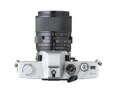 35mm camera, a stereotypical generic camera, de-branded and isolated on white with clipping path. This is an old used camera with worn edges, dust and scratches.