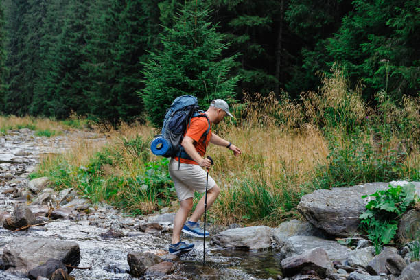 istock Male hiker crossing creek in forest 1663107653