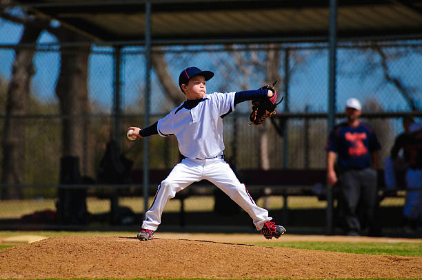 Youth baseball pitcher in wind up Youth baseball pitcher in wind up wearing white jersey. baseball pitcher stock pictures, royalty-free photos & images