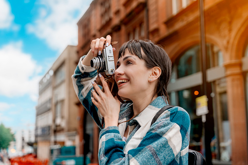 woman in blue shirt and cap with backpack  walking around  city, taking photos, selfie, having fun as tourist Lifestyle concept