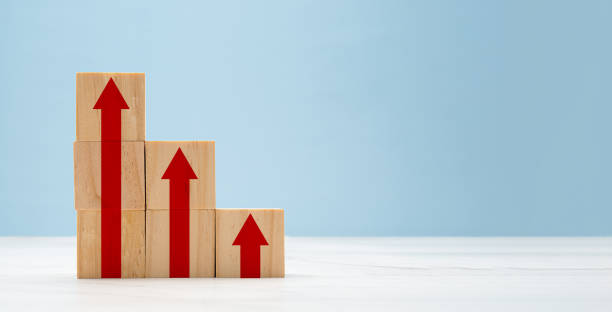 istock Wooden cubes with red arrows up a point on a marble floor over a light blue background 1663124123