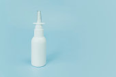 Nasal spray bottle on blue background with copy space. White plastic medical spray bottle, close up. the concept of health medicine and pharmacy. Production of medicines.