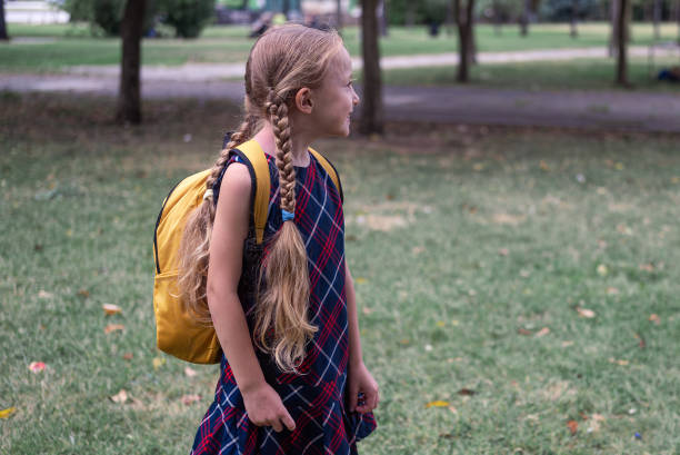 istock Cute smiling schoolgirl with backpack looks at path in green park resting after lessons 1663124697