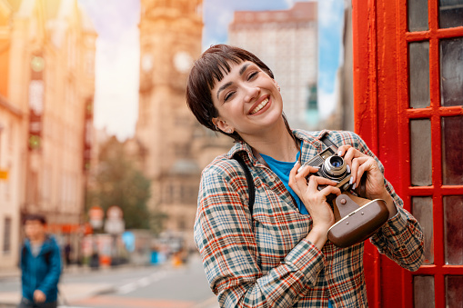 woman using old camera  against red phonebox traveling around English city Enjoying travel concept