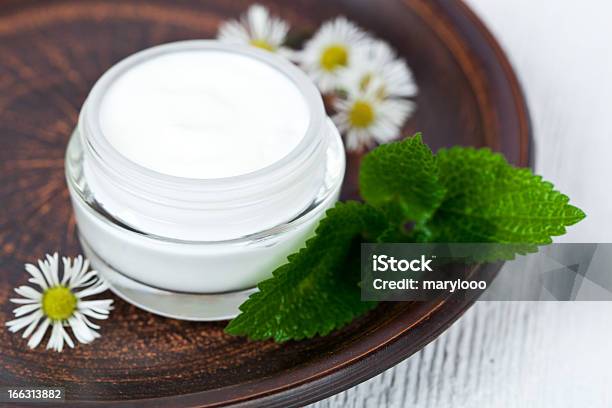 White Cream On Glass Bottle And Chamomile On A Wooden Plate Stock Photo - Download Image Now