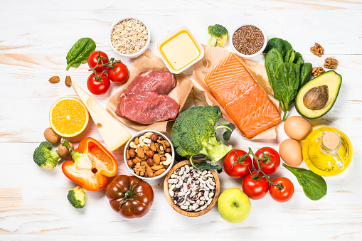 Healthy food products. Balanced nutrition. Salmon fish, beef, beans, nuts and vegetables with olive oil. Top view image at white table.