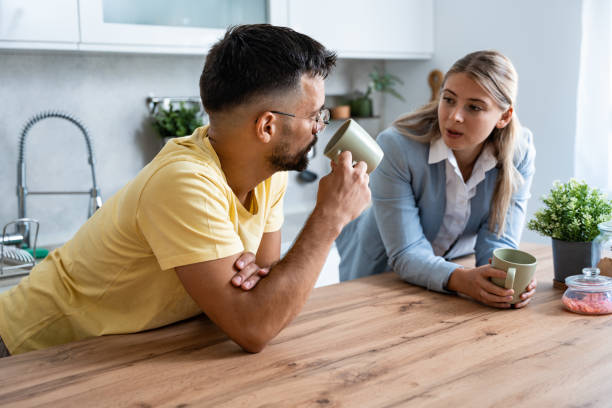istock Young man made first coffee for his girlfriend in formal wear who goes to work and they drink it together in the morning in the kitchen while discussing what they will do when she comes home from work 1663144900