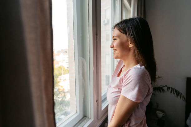 istock Young Woman Looking Out The Window After Waking Up In The Morning 1663155563