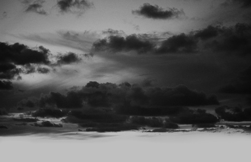 Black and white grain texture dramatic night sky with clouds. Nature light and shadow copy space grunge abstract background.