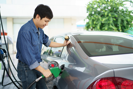 Car fueling at gas station. Refuel fill up with petrol gasoline. Petrol pump filling fuel nozzle in fuel tank of car at gas station. Petrol industry and service. Petrol price and oil crisis concept.