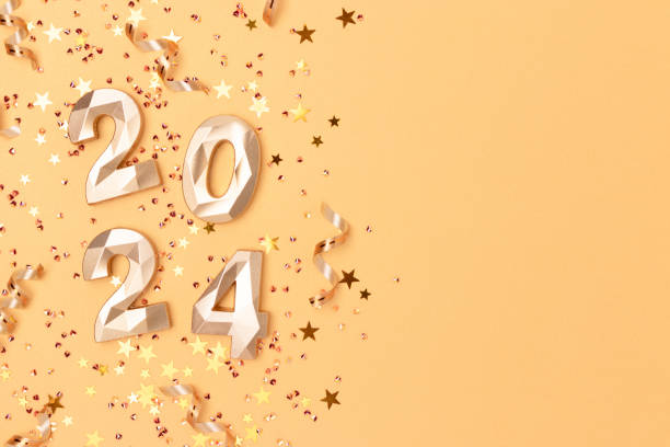 istock 2024 numbers, shiny stars confetti and ribbons on a golden background. 1663165073