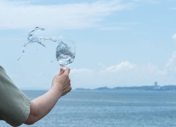 グラスから溢れる水 - overflowing water glass bottle ストックフォトと画像