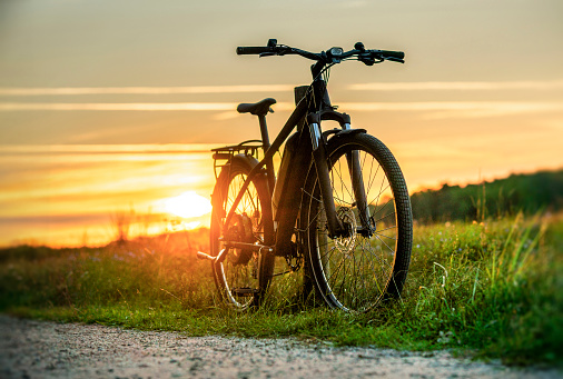 An e-bike leans on a bike path in beautiful nature on a sunny evening