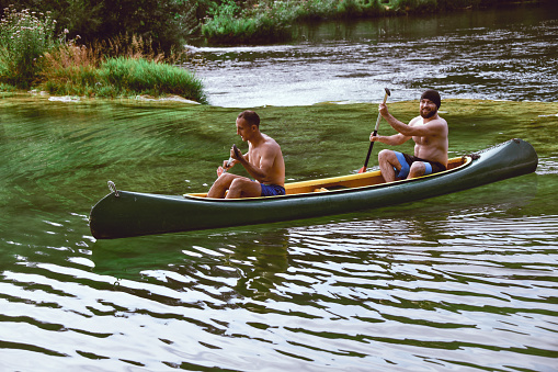Smiling Males Traveling River With Canoe