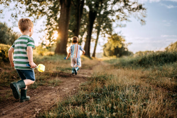 Rear view of two sibling boys running in forest together