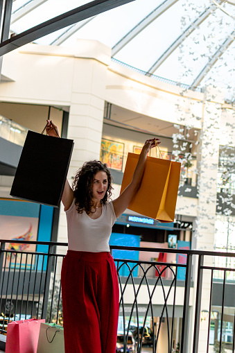 Embracing a shopping sensation, the young woman indulges in retail therapy at the mall, finding joy in every purchase and moment